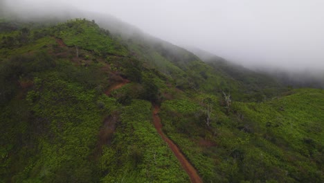 panoramic aerial above hiking couple climbing down dirt trail with misty clouds