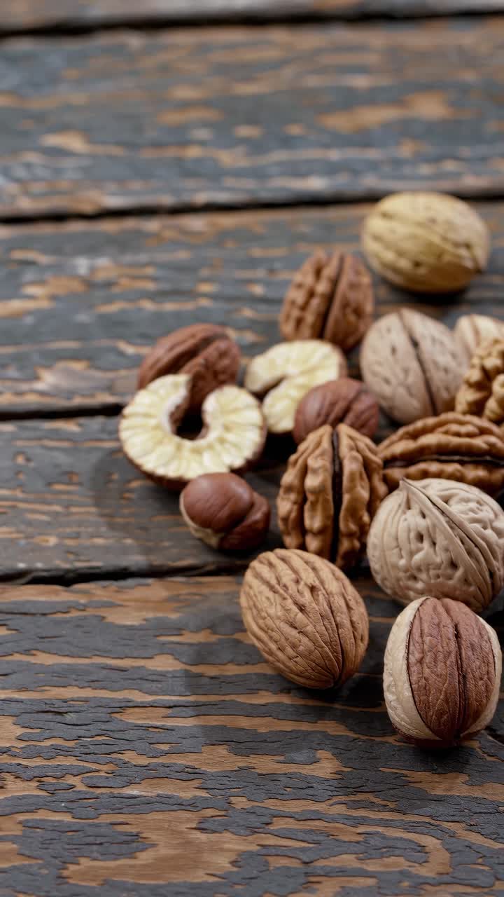 Close-up, top-down view of assorted nuts on rustic wooden surface. Ideal for a video on healthy