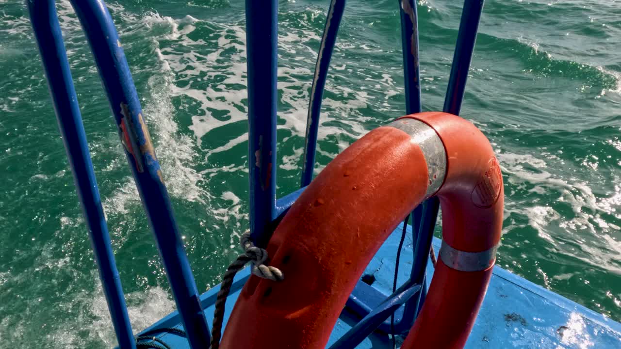 un vibrante anillo de vida naranja en un barco de pesca contra el mar turquesa cerca de phuket, tailandia. las olas iluminadas por el sol crean un telón de fondo dinámico
