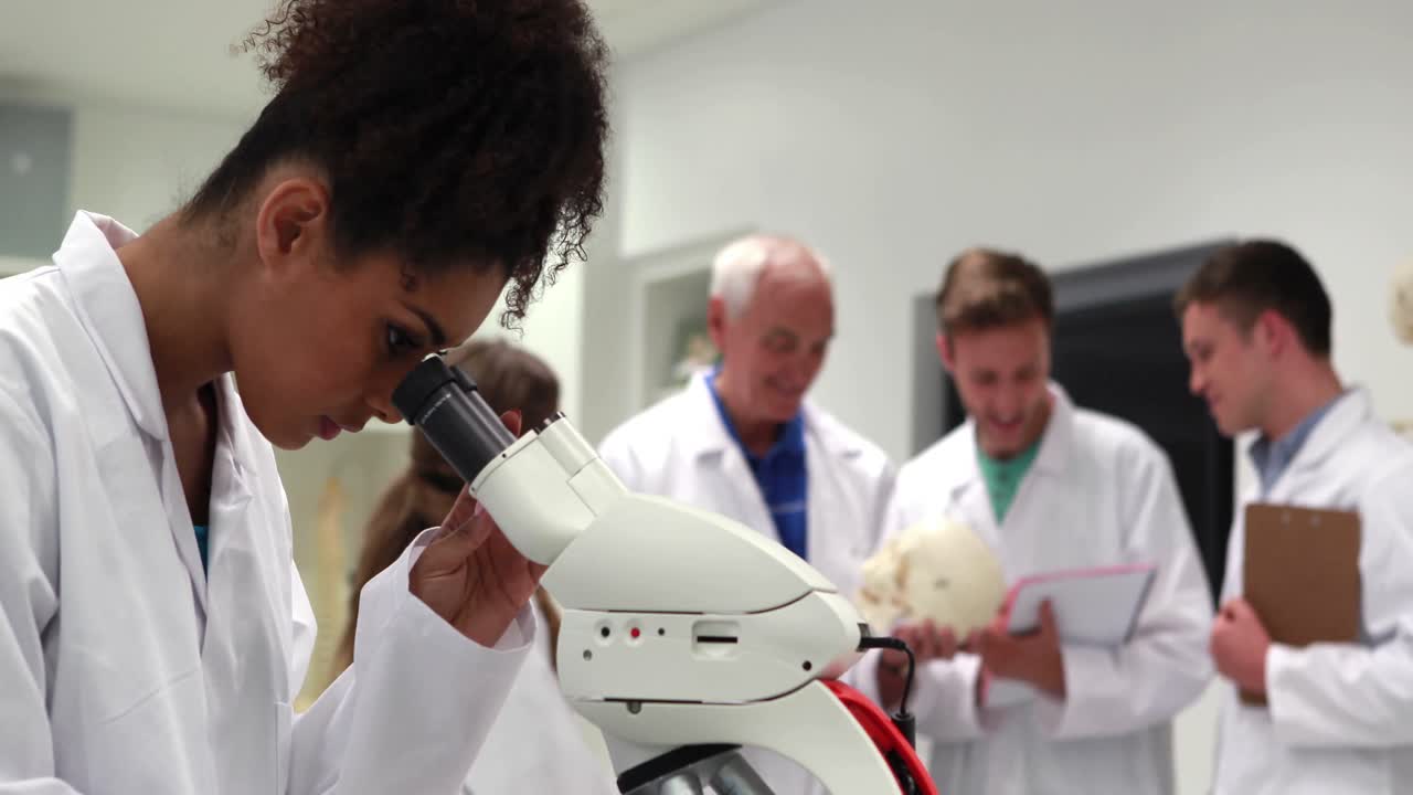 Bella studentessa di medicina che guarda attraverso il microscopio