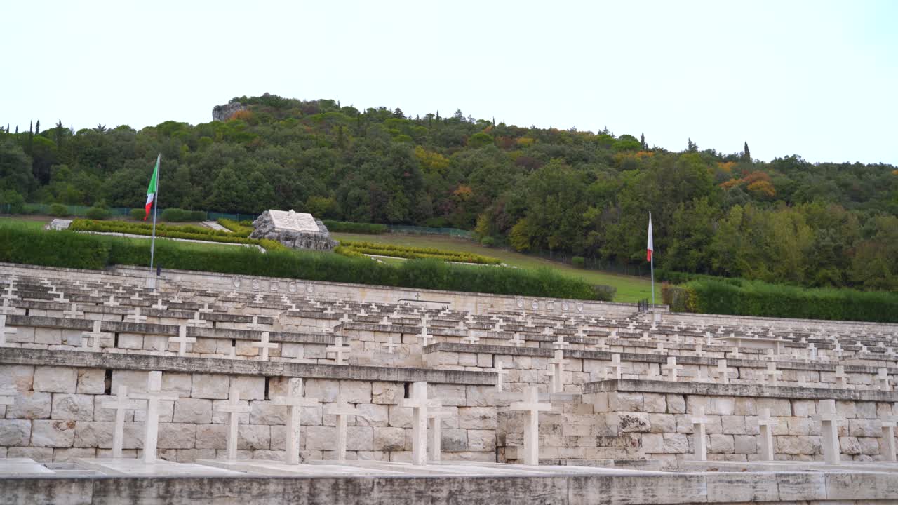 Two red, white and green Italian flags by rows of white stone crosses by tombs at Polish cemetery, Monte Cassino, Italy, static
