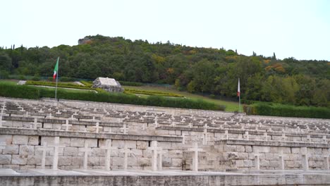 two red, white and green italian flags by rows of white stone crosses by tombs at polish cemetery, monte cassino, italy, static