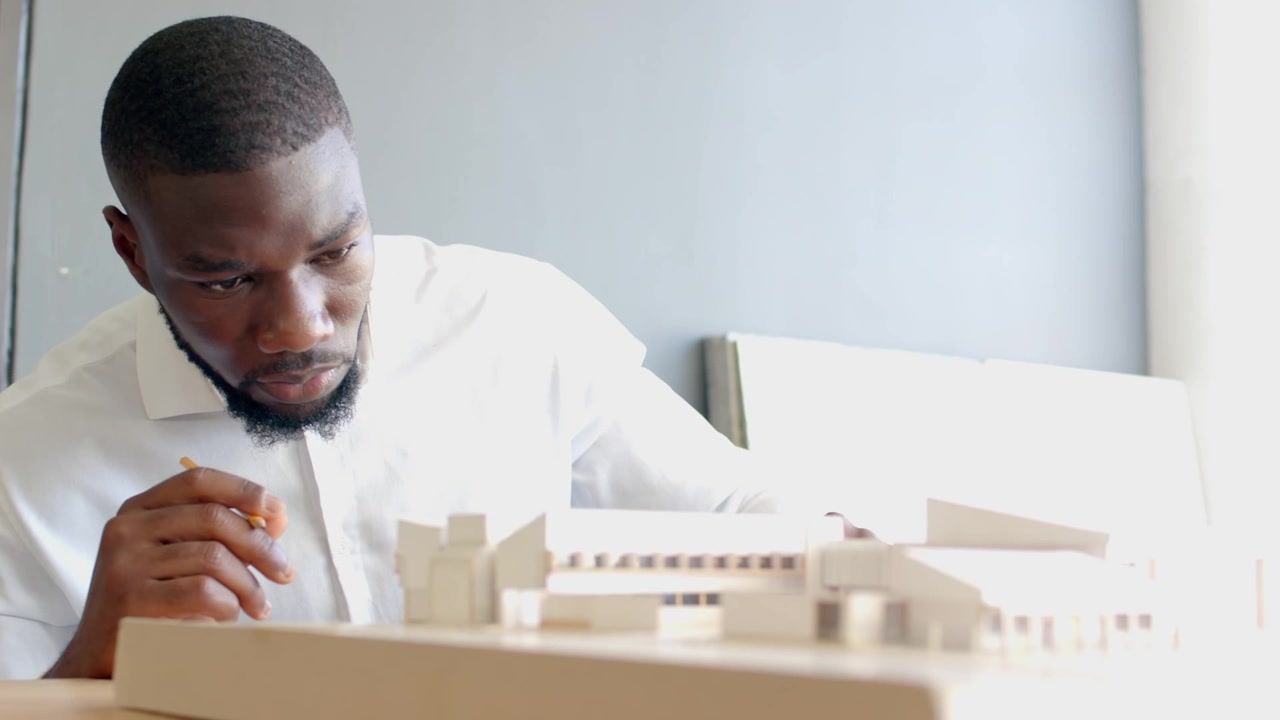 Architect examining model with pencil, adjusting part for plan, causing callouts growing over scene