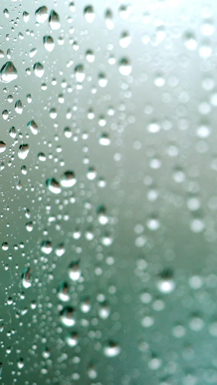 Rain falling on glass during rain storm. Vertical video