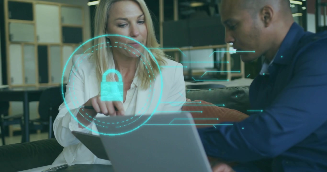 Woman tapping tablet over laptop and peer watching, projecting padlock hologram for security demo