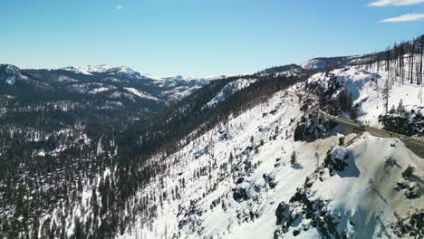 aerial drone view of high altitude mountain highway and valley below in winter