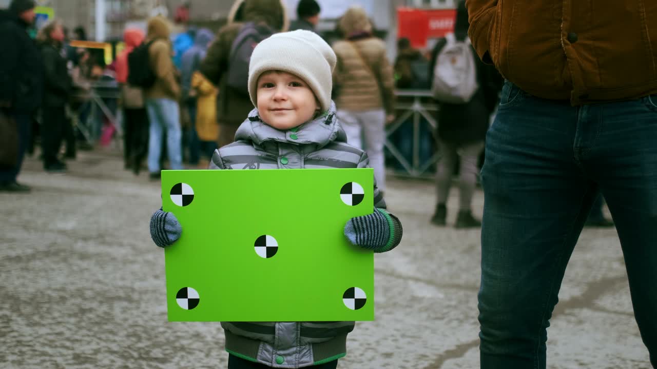 Smiling child with chromakey placard at political strike. Kid activist at rally.