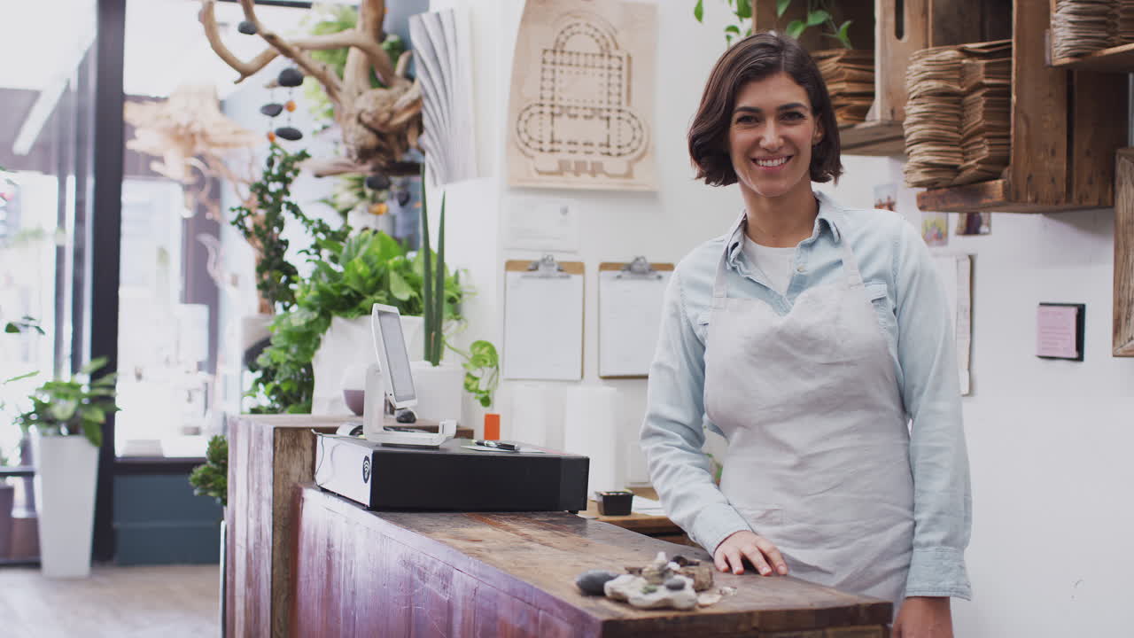 Retrato de una sonriente dependienta de pie detrás del mostrador de ventas de una floristería.