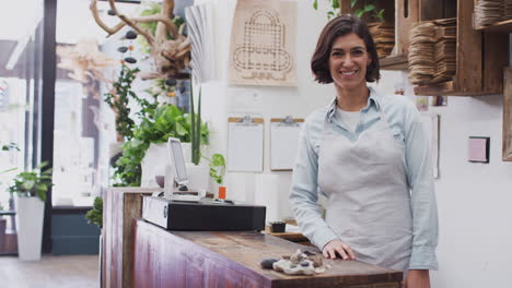 retrato de una asistente de ventas de sexo femenino sonriente de pie detrás del mostrador de ventas de la tienda de flores