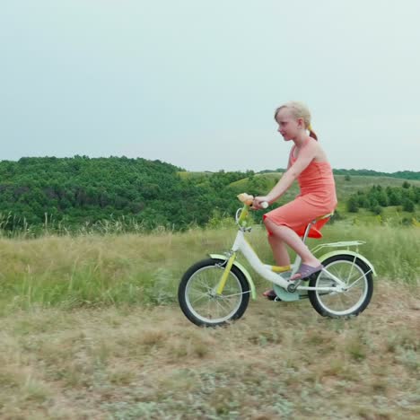 Ein-Cooles-Mädchen-In-Einem-Rosa-Kleid-Fährt-Mit-Dem-Fahrrad-Auf-Dem-Land