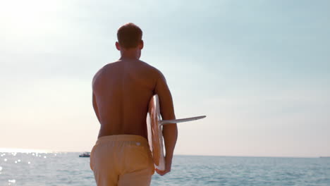 hombre con una tabla de surf y corriendo hacia el mar