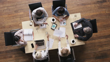 Top-view-diverse-business-people-meeting-at-boardroom-table-discussing-financial-report