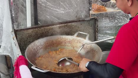 street food vendor cooking noodles in wok