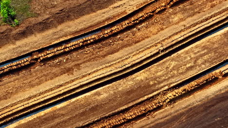stacked peat bricks drying in straight rows across brown peat extraction field from above