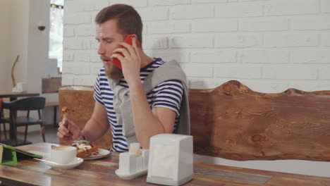 hombre tomando el desayuno en un café mientras habla por teléfono