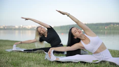 two women stretching outdoors by a lake