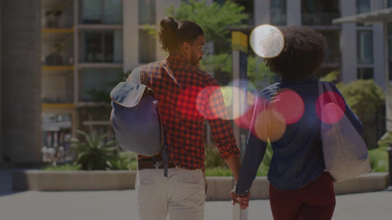 Man and woman holding hands, walking toward building, man glancing, bokeh obscuring for marketing