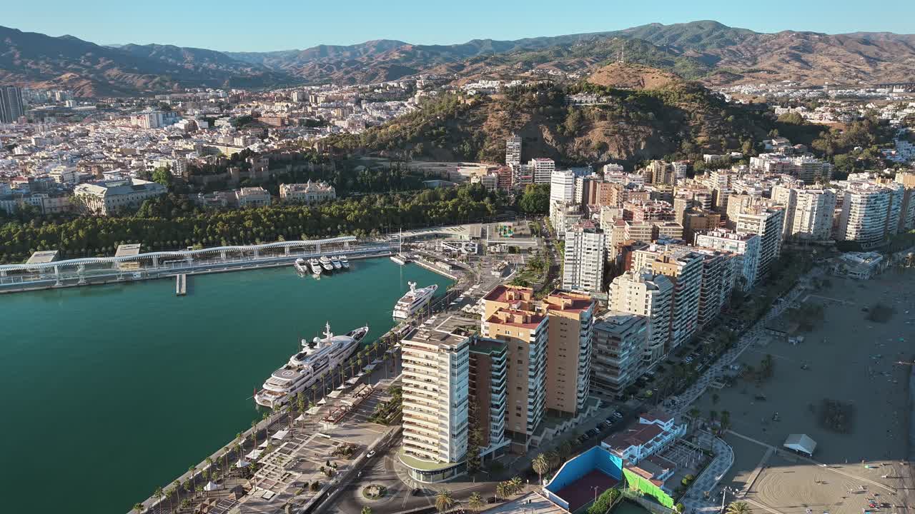 Cruise ships anchored off the coast of Malaga city. Port with tall skyscrapers on a sunny day from a drone
