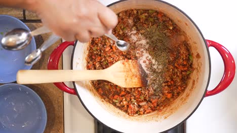 adding salt into the roux as it simmers to prepare the sauce for a seafood and andouille sausage gumbo - overhead view gumbo series