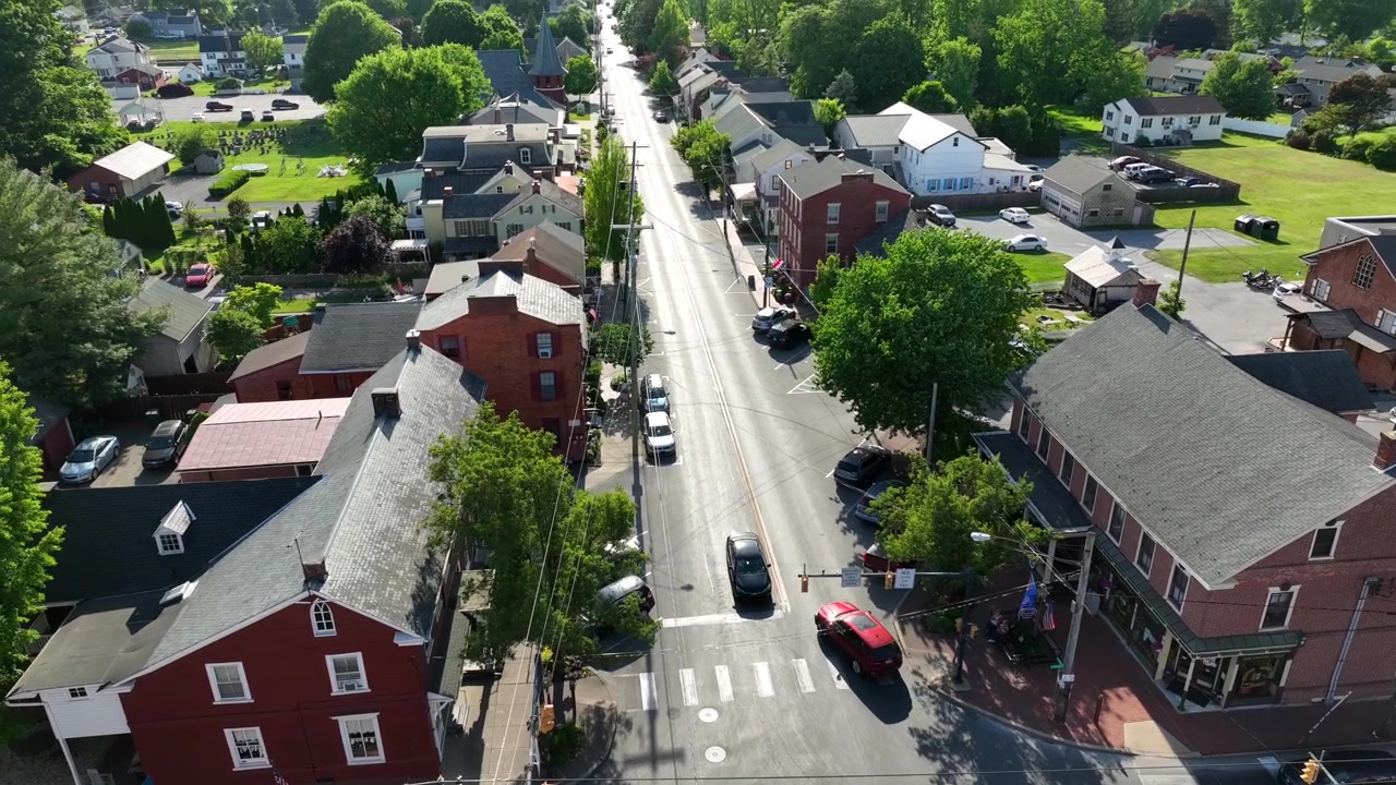 Aerial view of the small town of Strasburg, Pennsylvania, featuring a main roadway, homes, businesses, church and cemetery.