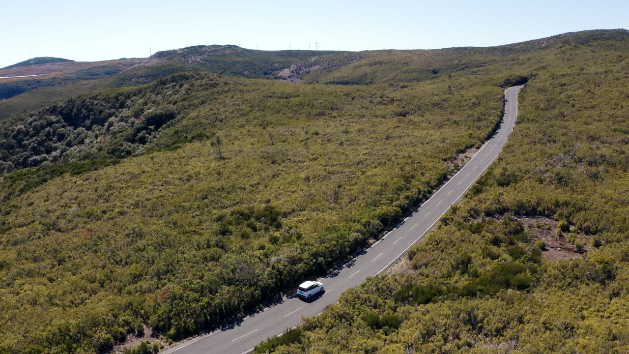 imágenes de drones de 4k de un coche familiar blanco que va por una carretera vacía a través de un paisaje salvaje