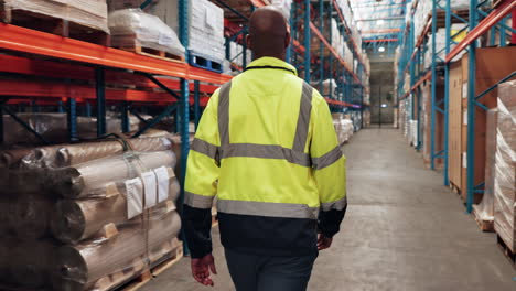 a man walks through a warehouse aisle.