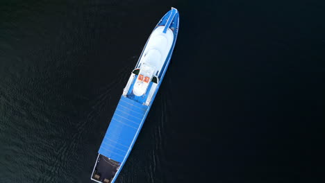 aerial view of a blue boat moving on dark water