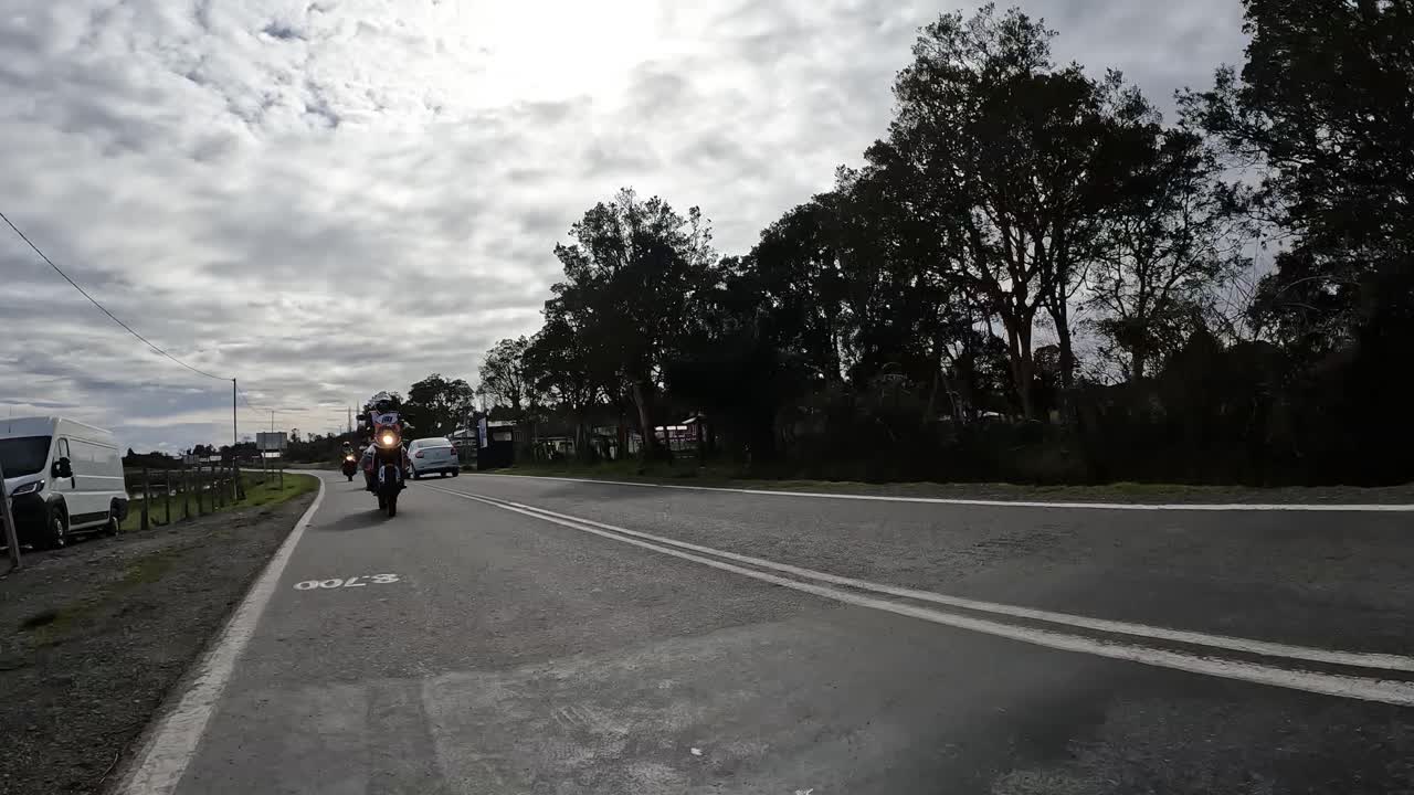 Group of adventure motorcyclists riding on a paved rural road on a cloudy day. Northern Chilean Patagonia