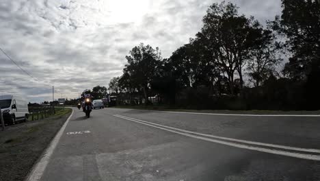 group of adventure motorcyclists riding on a paved rural road on a cloudy day. northern chilean patagonia