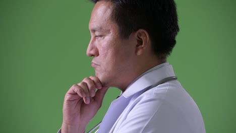 성숙한 일본인 남성, 초록색 배경의 의사
