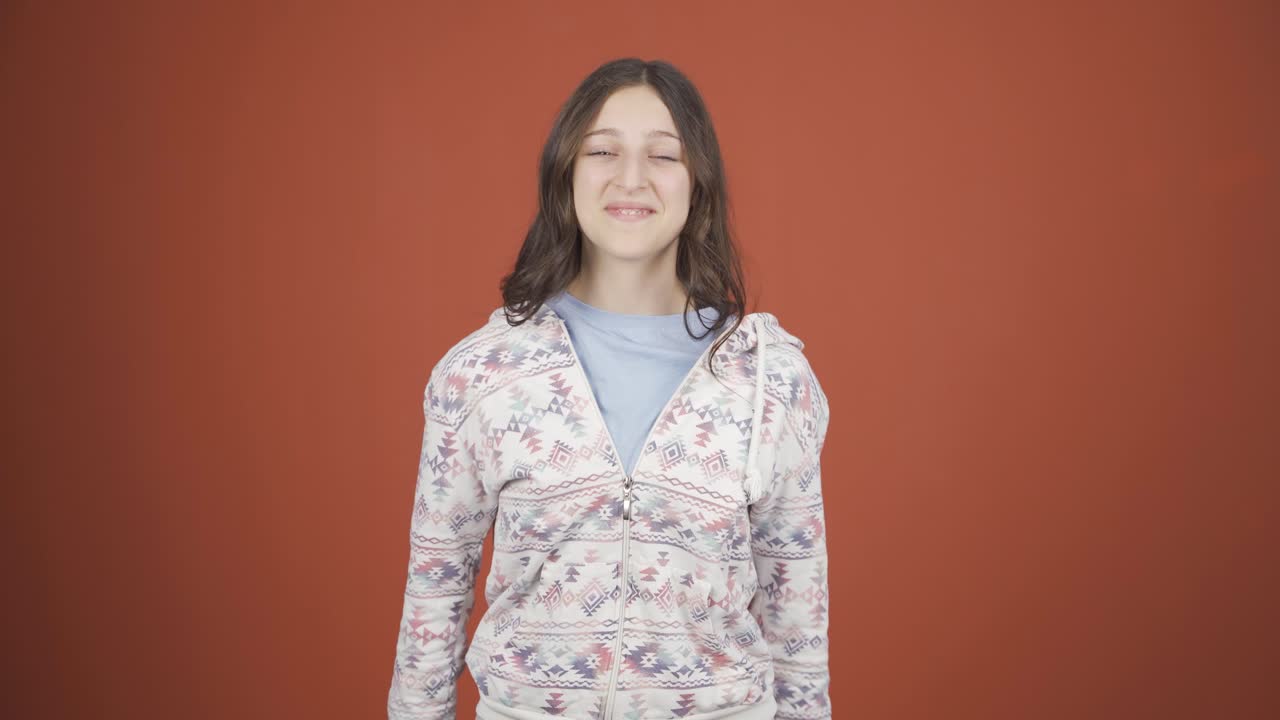 자신감의 표시를 하는 카메라를 보는 젊은 여성.