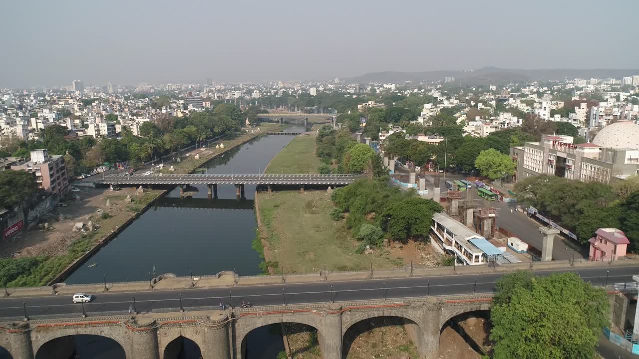 Aerial 4K view of bridge and city in India during nationwide lockdown to avoid transmission of the coronavirus - COVID-19 outbreak - Pune, Maharashtra with polluted river containing drained wastewater
