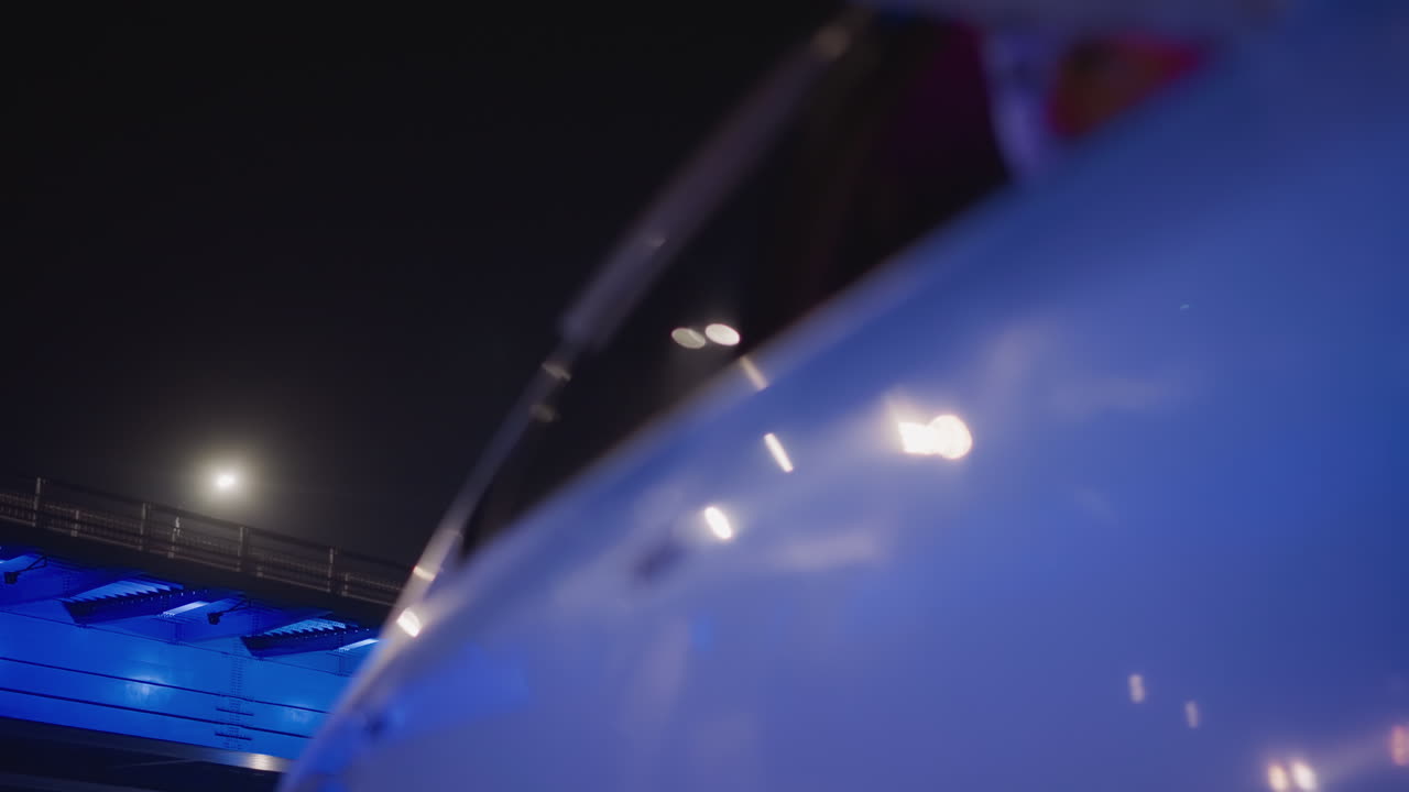 night blue sedan parked under illuminated bridge, hand holding keys near door handle while person steps away in jeans, pink interior glow and neon reflections, cinematic departure and nightlife