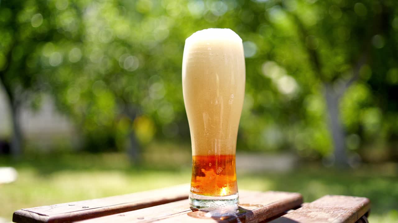 Full glass of white foam from beer. Process of becoming beer beverage from foam in the glass on blurred background. Bubbles and foam in beer glass.