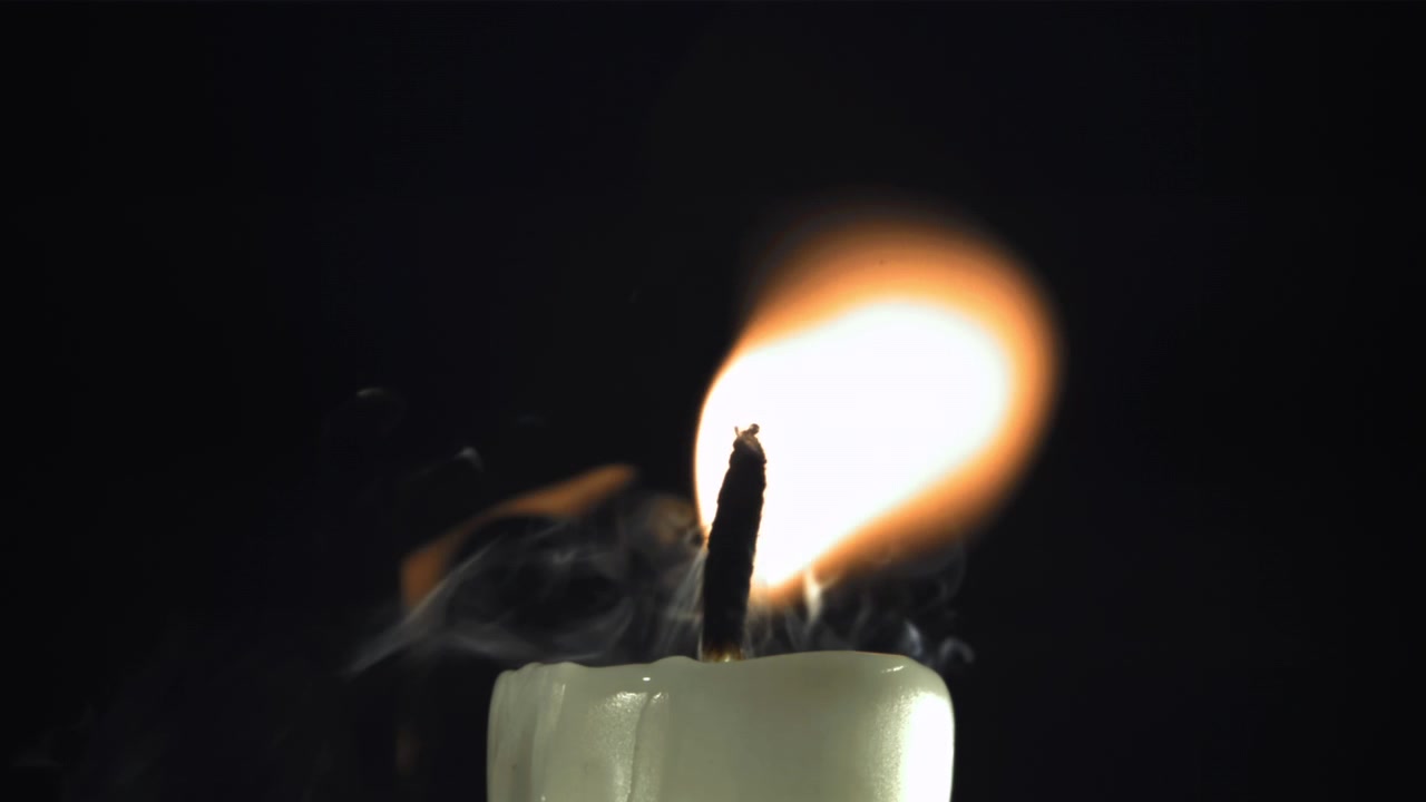 Primo piano al rallentatore di una fiamma di candela che si spegne con fumo