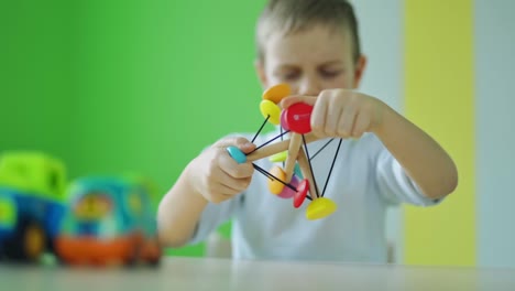 bright toy in kid's hands. little boy playing with wooden toy in the room. adorable child playing with a colorful toy. childhood concept.