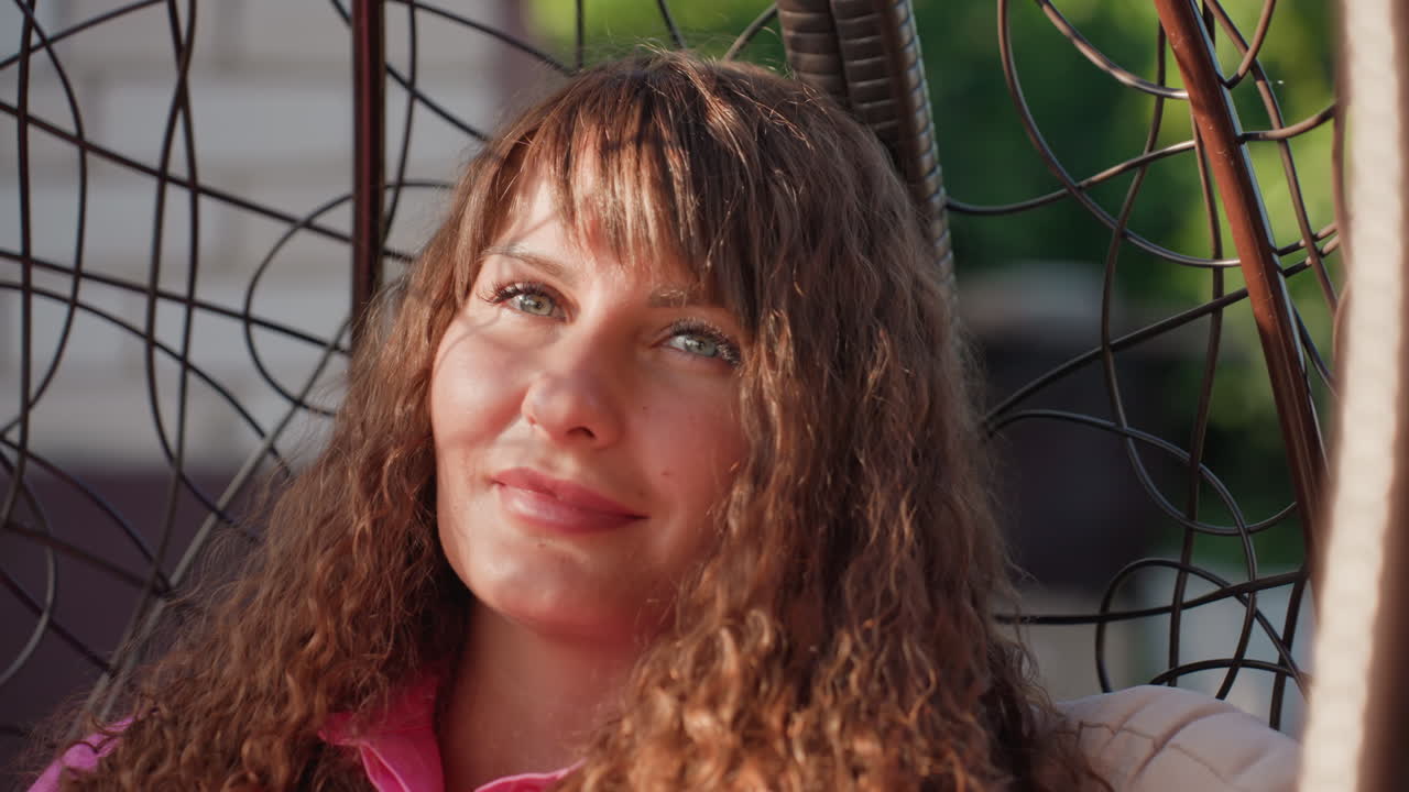 Woman Relaxes Outdoors, Happy Woman Enjoying Peaceful Outdoor Moment, Casual Portrait Of Woman In Cozy Hanging Chair, Relaxed Woman Smiling Gently In Leafy Environment During Sunny Afternoon