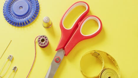 video of tape measures, needles, pins, scissors, thimble and sewing threads on yellow background