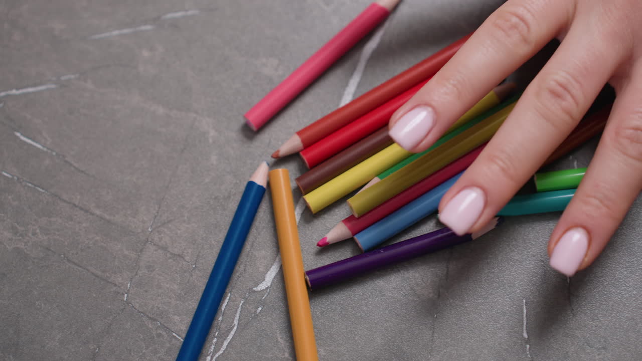 Close up of student hand arranging colorful pencils on table with natural light, symbolizing childhood creativity, learning, education and focus through playful interaction with art materials