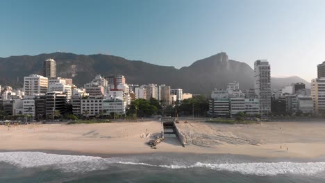 panorámica aérea lenta hacia abajo del horizonte de río de janeiro al amanecer con la montaña corcovado y el canal que va desde el lago de la ciudad hasta la playa de leblon visto desde arriba del océano