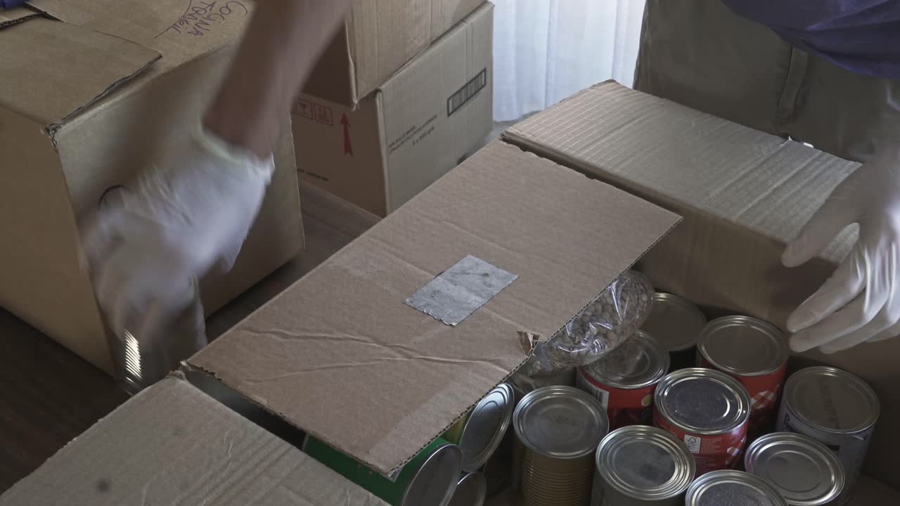 Volunteer Packing Canned Food and Groceries into Donation Boxes