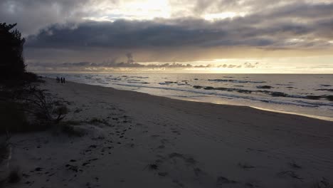 Hermosa-Toma-Aérea-Volando-Sobre-Una-Playa-Al-Atardecer-En-La-Costa-Del-Mar-Báltico,-Alto-Contraste,-Clima-Nublado,-Disparo-De-Drones-De-Gran-Angular-A-Baja-Altitud-Avanzando-Sobre-La-Playa-De-Arena