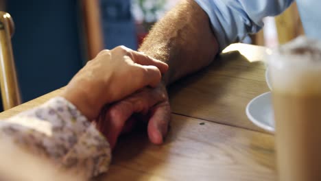 Senor-couple-holding-hands-in-cafe-4k