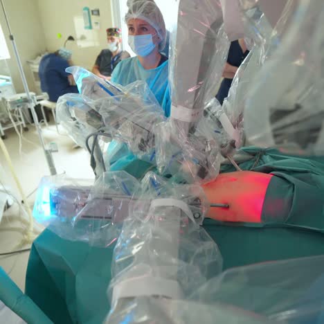 surgical process with medical robot. robotic equipment during operation on a patient in clinic. red light on patient's belly during robotic surgery