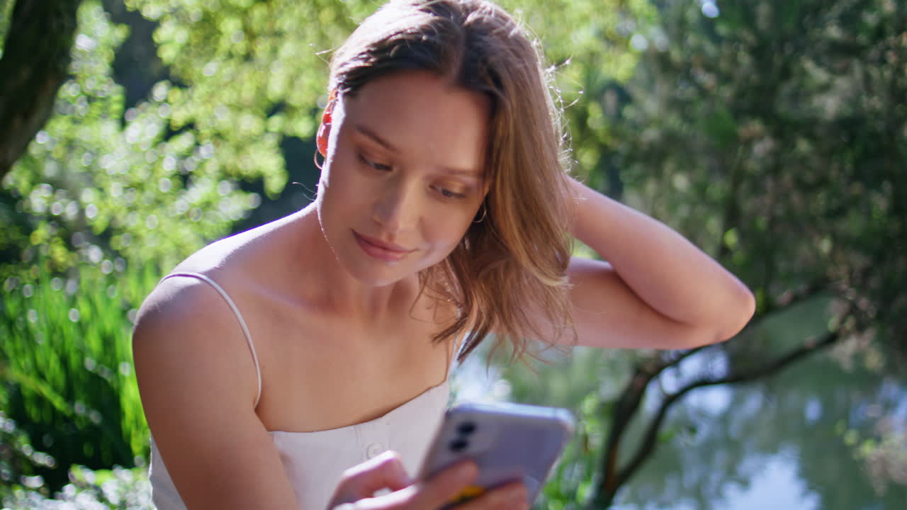 Relaxed lady watching social media at mobile phone sitting waterfront closeup