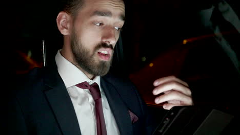 businessman having a video conference on tablet sitting in the back seat of his limousine