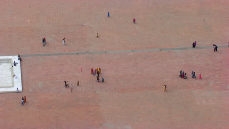 Lahore,-Pakistan,-Close-up-view-of-ground-to-the-minarets-of-the-Badshahi-Mosque,-Visitors-ladies,-gents-and-children-are-in-the-Mosque,-Worshipers-in-the-ground-of-the-Mosque,-black-kites