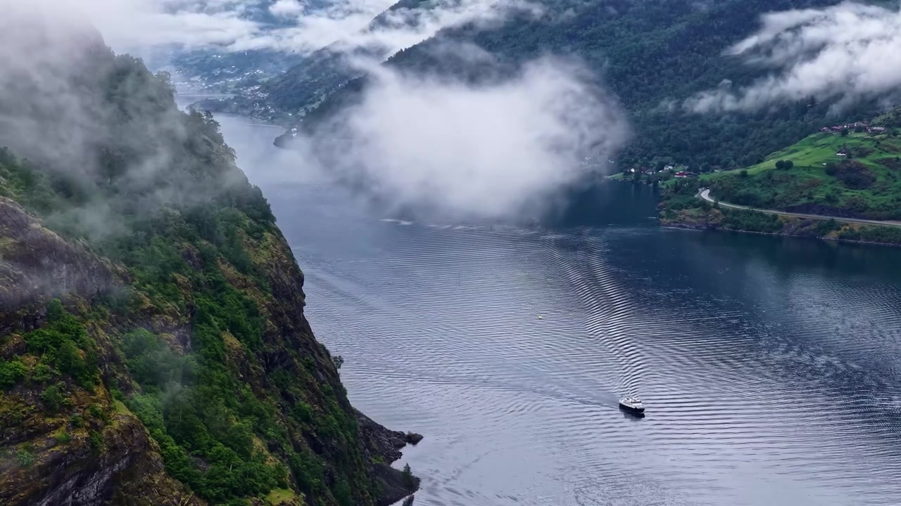 Timelapse udara kapal yang bergerak melalui fyord Norwegia, pegunungan dramatis, kabut, pemandangan indah.