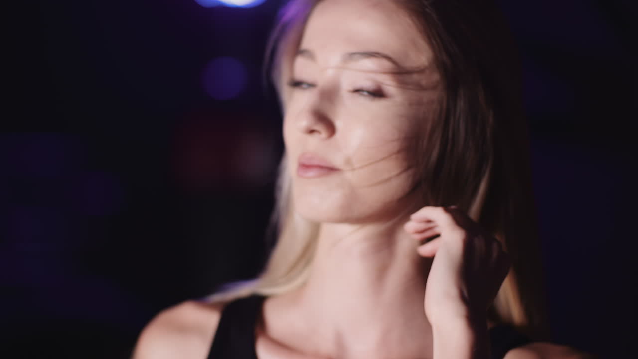 cámara lenta de atleta femenina atractiva sonriente moviendo las manos a través del cabello en el club de salud