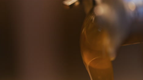 thick honey pouring into jar close-up